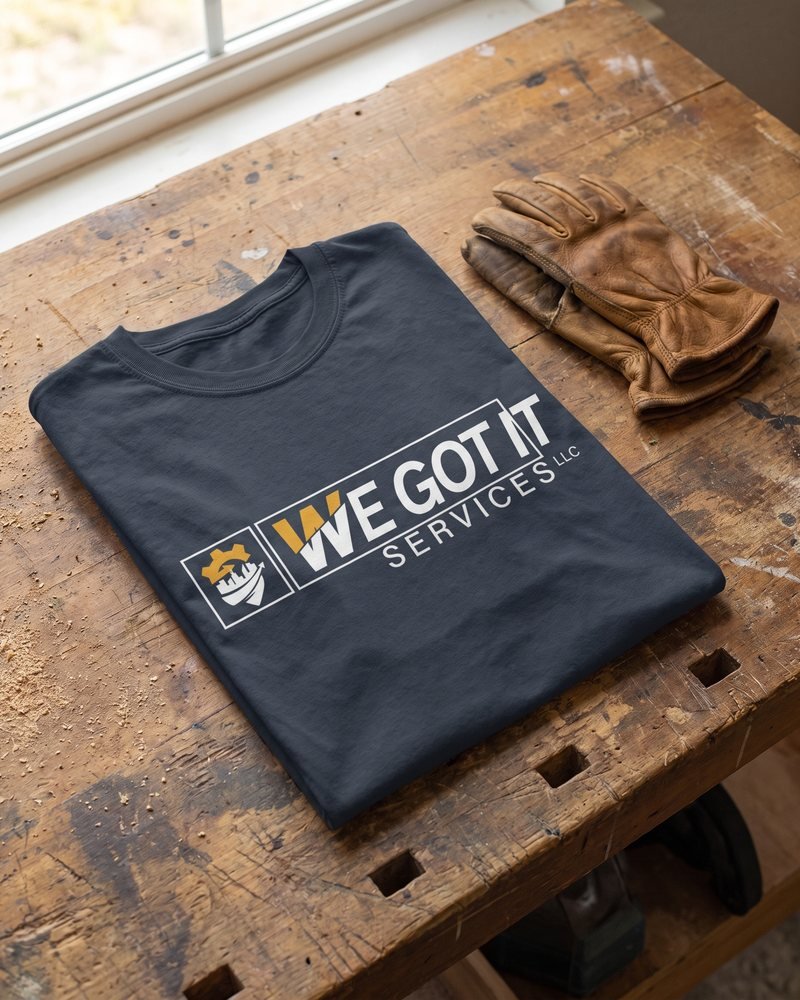 Mockup of the We Got It Services logo printed on a navy work t-shirt