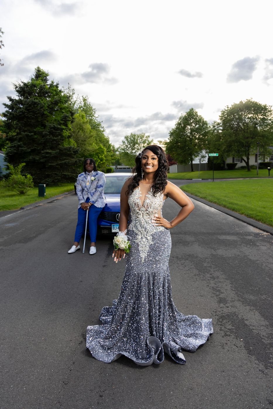 Woman in a sequin gown on a suburban street with her date by the car